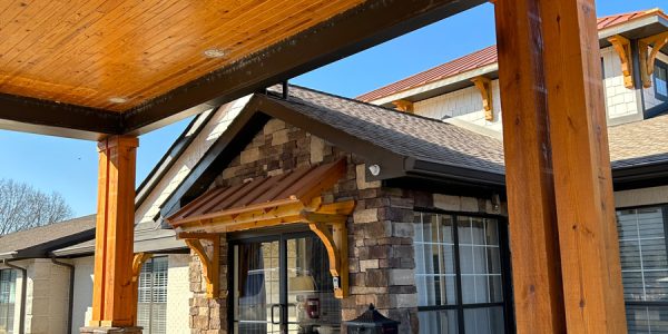 Covered entrance with timber posts, stone veneer columns, glass double doors and a paved walkway